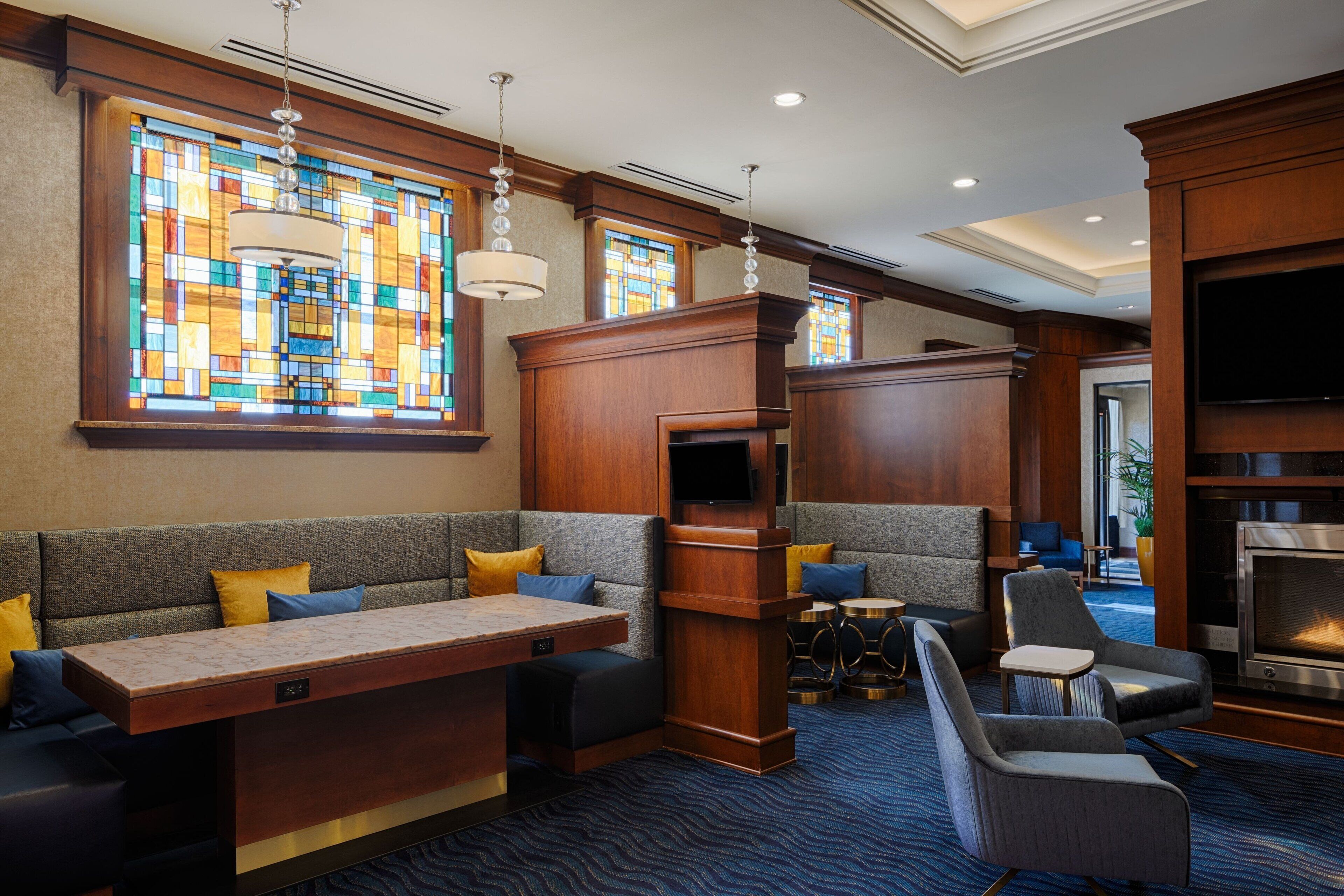 A hotel lobby with a seating area, a fireplace, and stained glass windows.