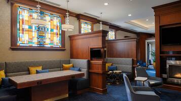 A hotel lobby with a seating area, a fireplace, and stained glass windows.