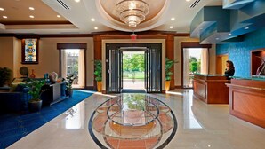 A hotel lobby with a reception desk, a chandelier, a large glass table, and a blue carpet. - Residence Inn by Marriott Cincinnati Downtown/The Phelps (Cincinnati)