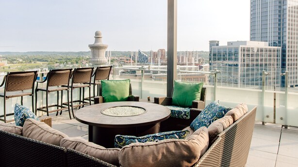 A rooftop terrace with wicker furniture, a round table, and a view of the cityscape. - Residence Inn by Marriott Cincinnati Downtown/The Phelps (Cincinnati)