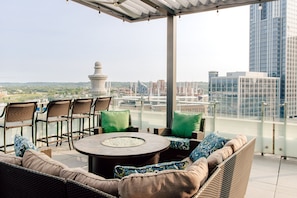 A rooftop terrace with wicker furniture, a round table, and a view of the cityscape. - Residence Inn by Marriott Cincinnati Downtown/The Phelps (Cincinnati)