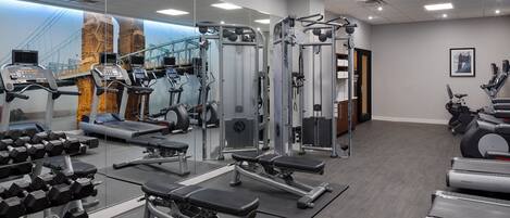 Un gimnasio con cintas de correr, máquinas de pesas y mancuernas.