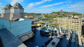 A rooftop terrace with outdoor seating, a view of the cityscape, and a large building in the background.