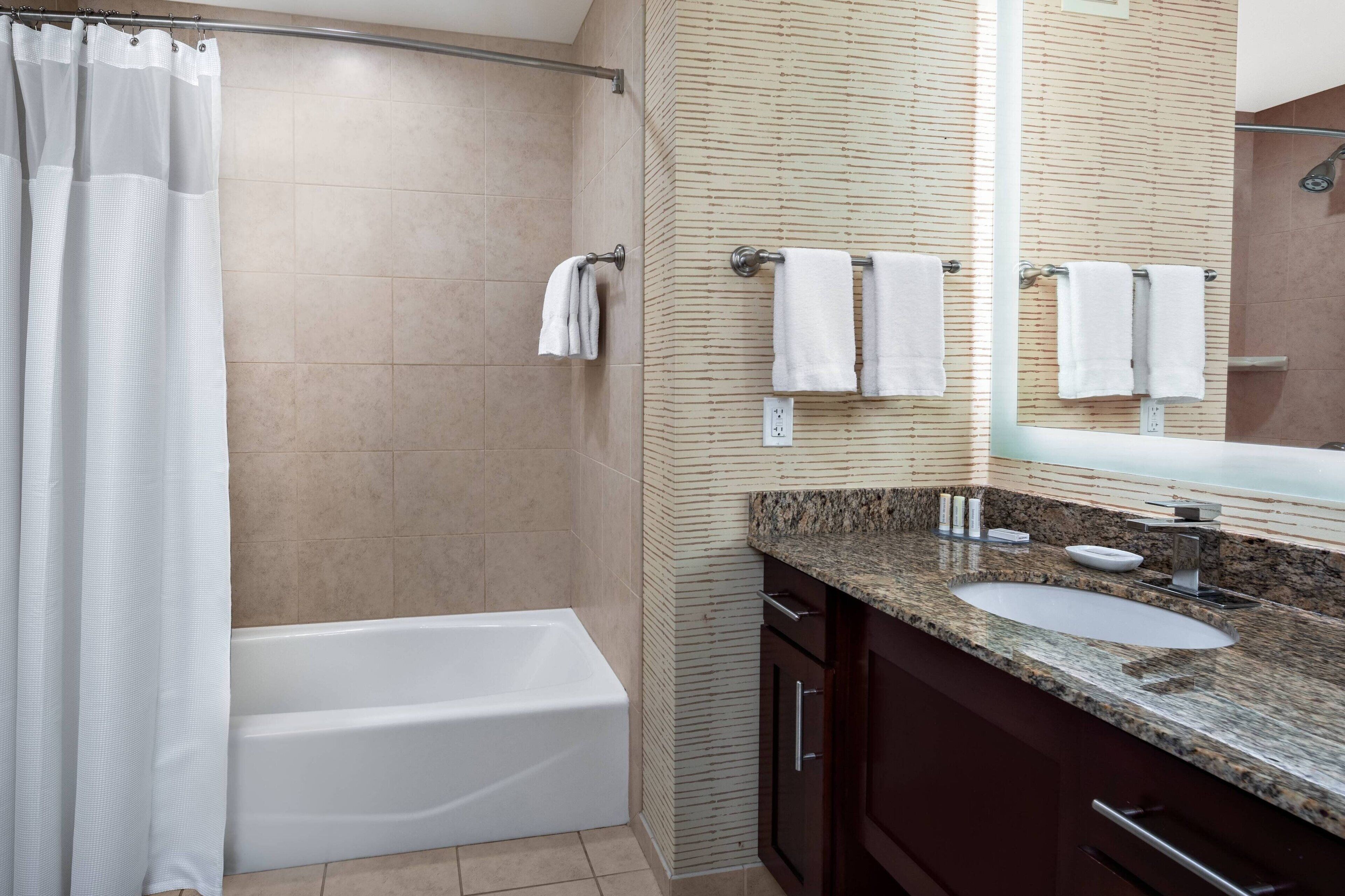 A modern bathroom with a bathtub, a sink, and a mirror.
