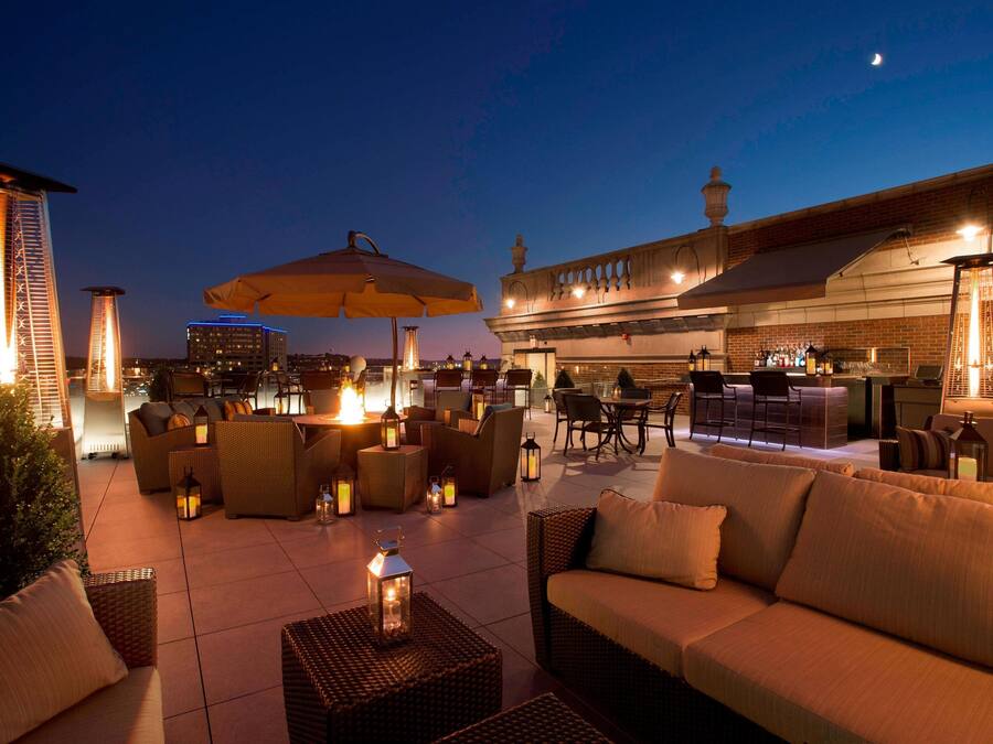 An outdoor patio area with wicker furniture, lanterns, and a bar area.