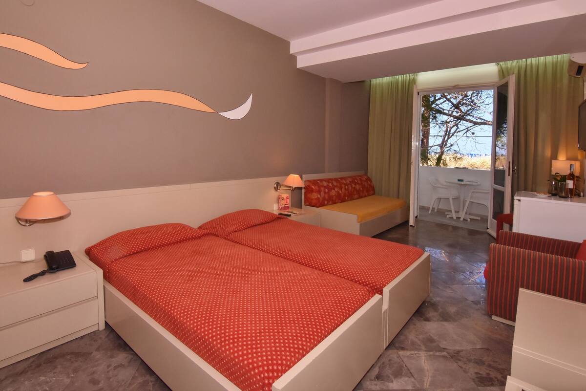 A hotel room with a large bed, a desk, and a view of the outdoors.