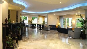 A spacious lobby with a marble floor, seating areas, and large windows providing natural light. - Mantenia Hotel (Rethymno)