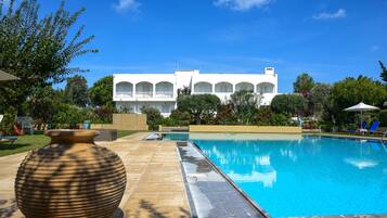 Alberca al aire libre, sombrillas en la alberca y camastros