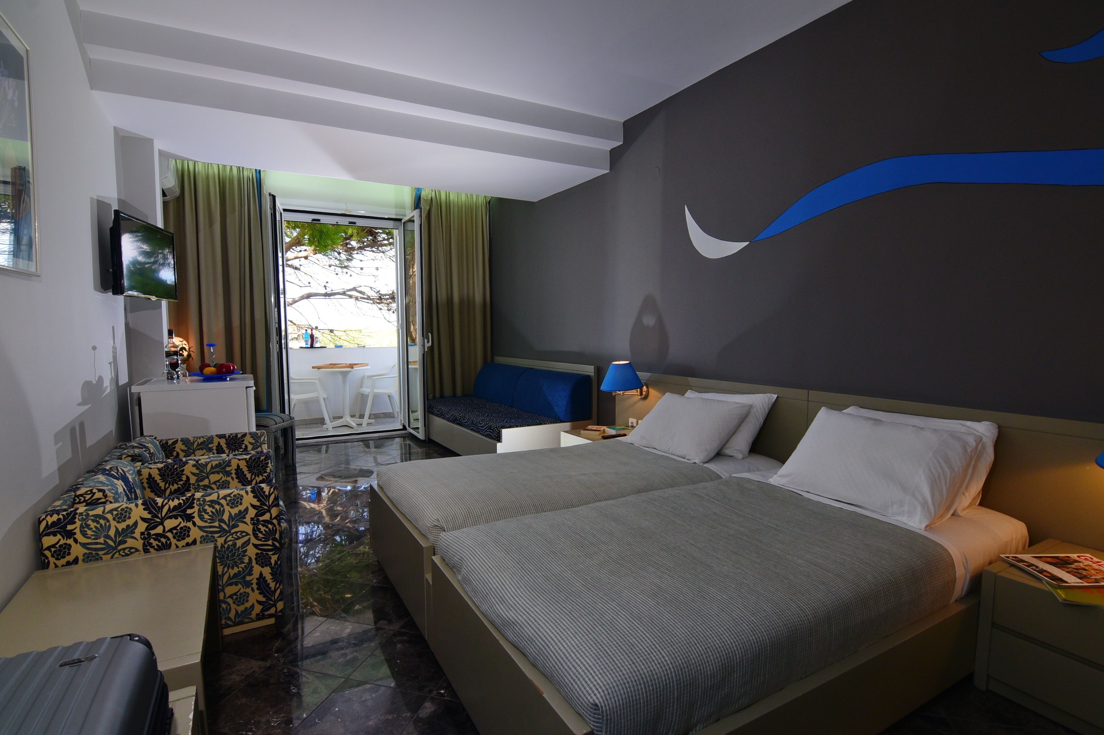 Une chambre d’hôtel avec deux lits, un bureau, une télévision et une vue sur l’extérieur.