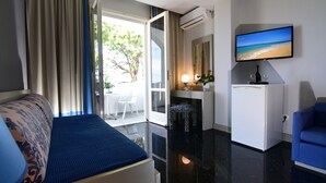 A hotel room with a bed, a desk, a chair, a TV, and a view of the outdoors. - Mantenia Hotel (Rethymno)