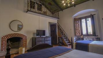 Ein Zimmer mit Kamin, Bett, Fernseher und einer Treppe.