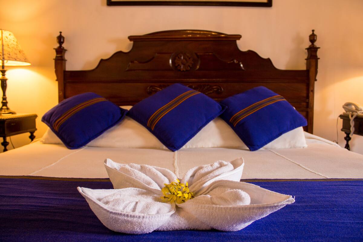 A neatly made bed with blue pillows and a floral arrangement in the center.