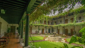 A courtyard with a fountain, potted plants, and a covered seating area with tables and chairs. - Hotel Posada de Don Rodrigo Antigua (Antigua Guatemala)