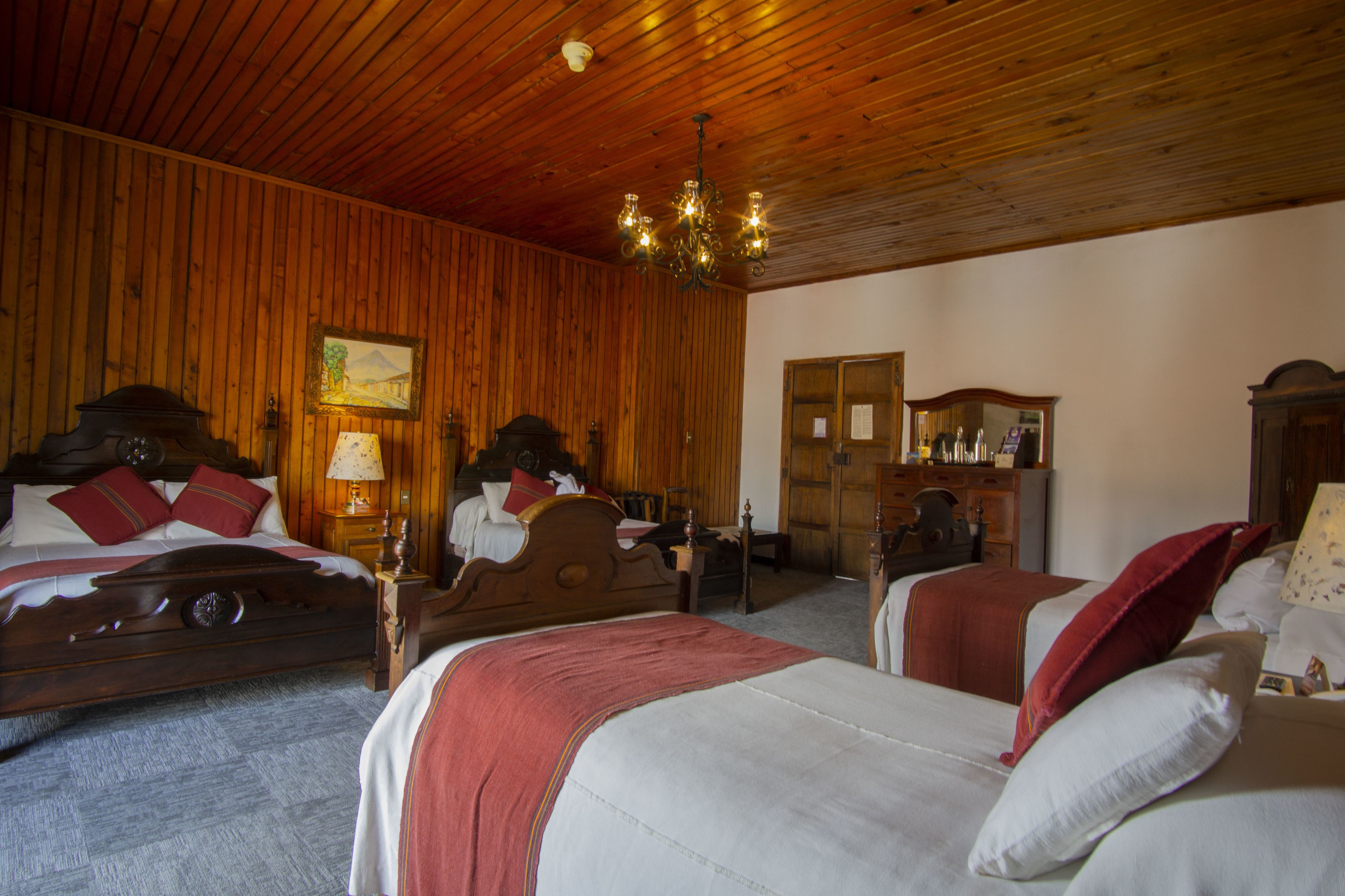 A room with two wooden beds, a wooden ceiling, and a chandelier.