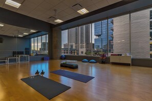 A spacious gym with large windows, wooden floors, and exercise equipment.