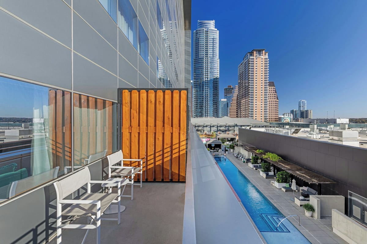 A rooftop pool area with modern seating and a view of high-rise buildings.