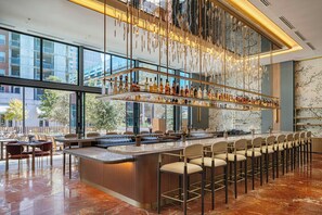 Un bar moderno con una barra larga, varios taburetes y una variedad de botellas.