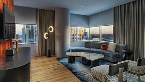 A modern living room with a curved reception desk, a sectional sofa, and a large window offering a city view. - W Austin (Austin)