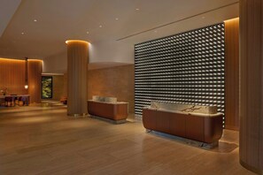 A modern lobby with a reception desk, seating area, and a decorative wall with a pattern of lights.