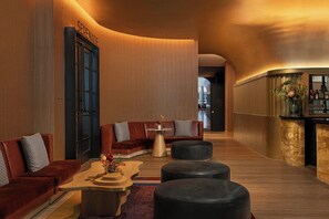 A modern lounge area with a curved ceiling, a sofa set, a coffee table, and a bar area with a vase of flowers.
