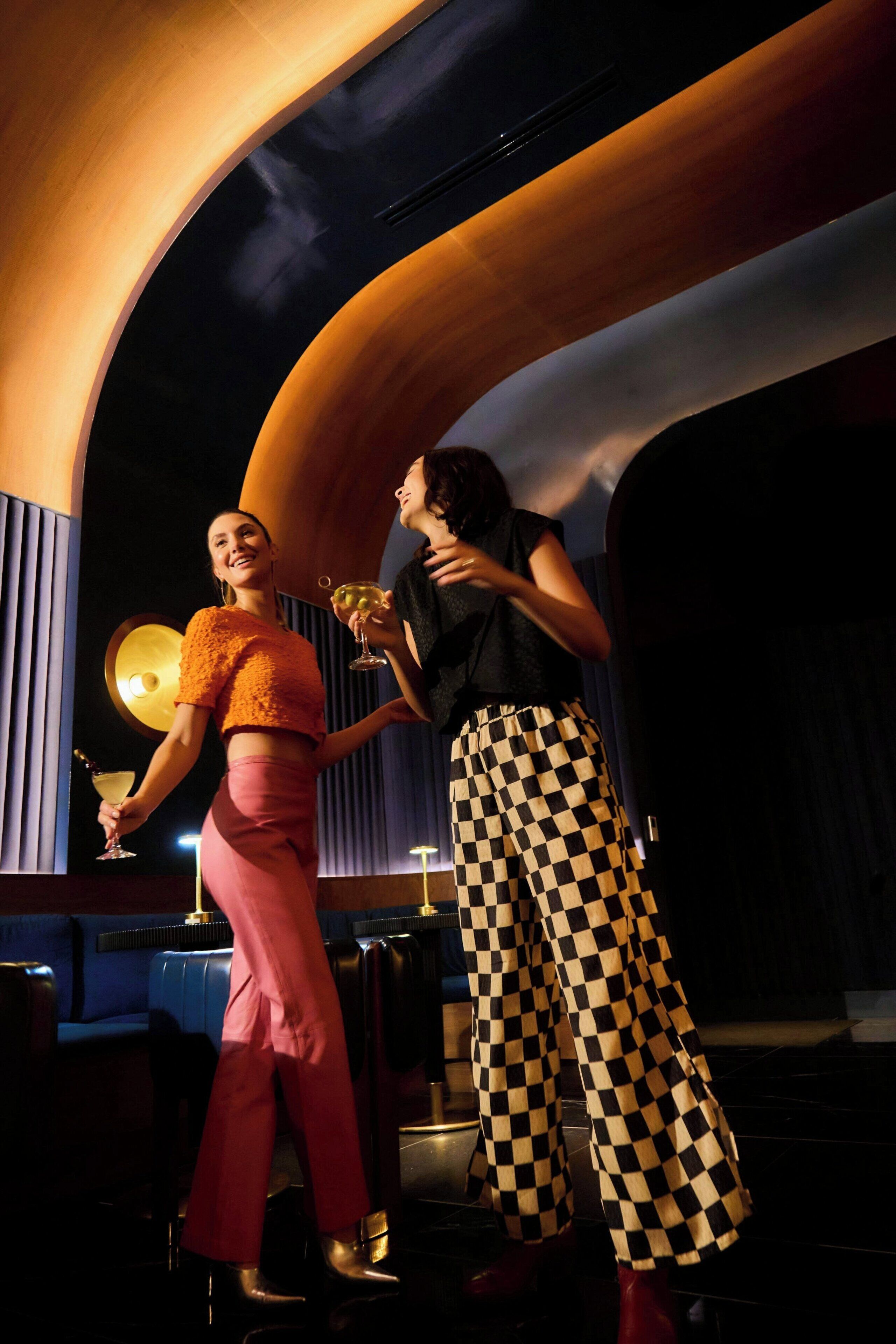 Two people in a dimly lit room with a curved ceiling and a large circular light fixture.