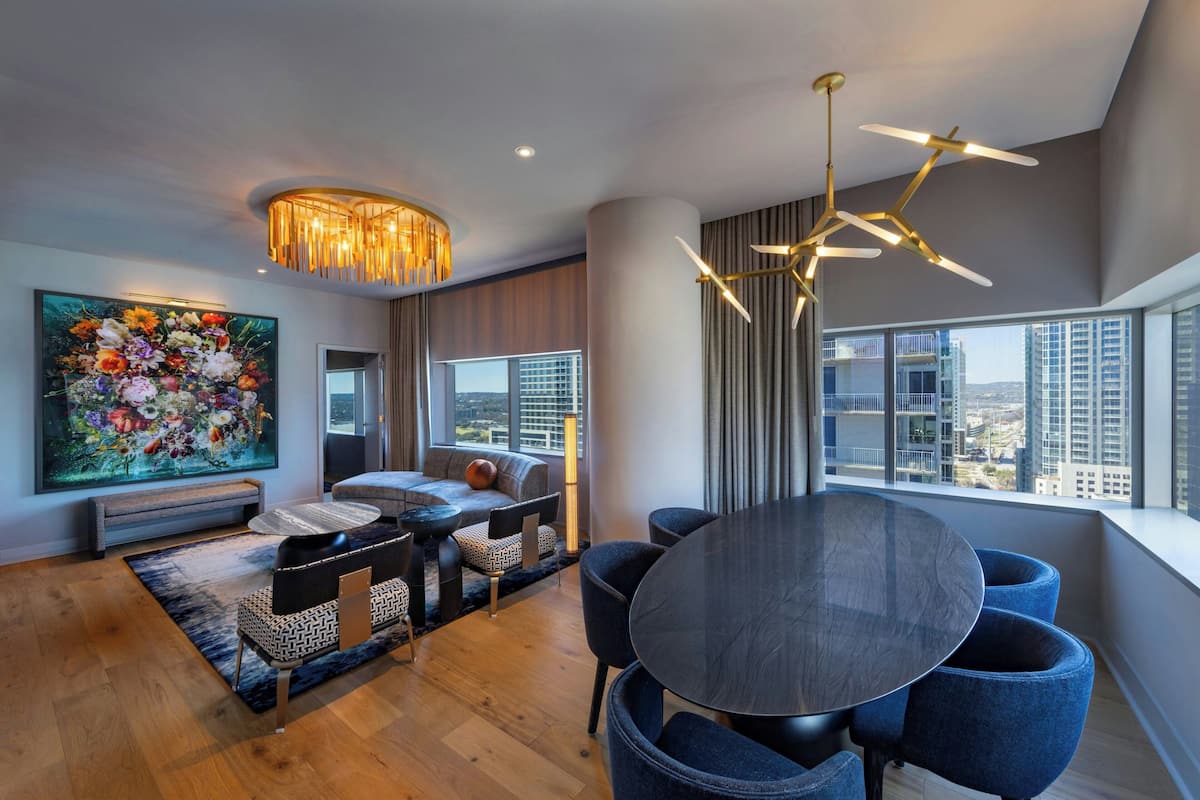 A modern living room with a large window, a dining area, and a sofa set.