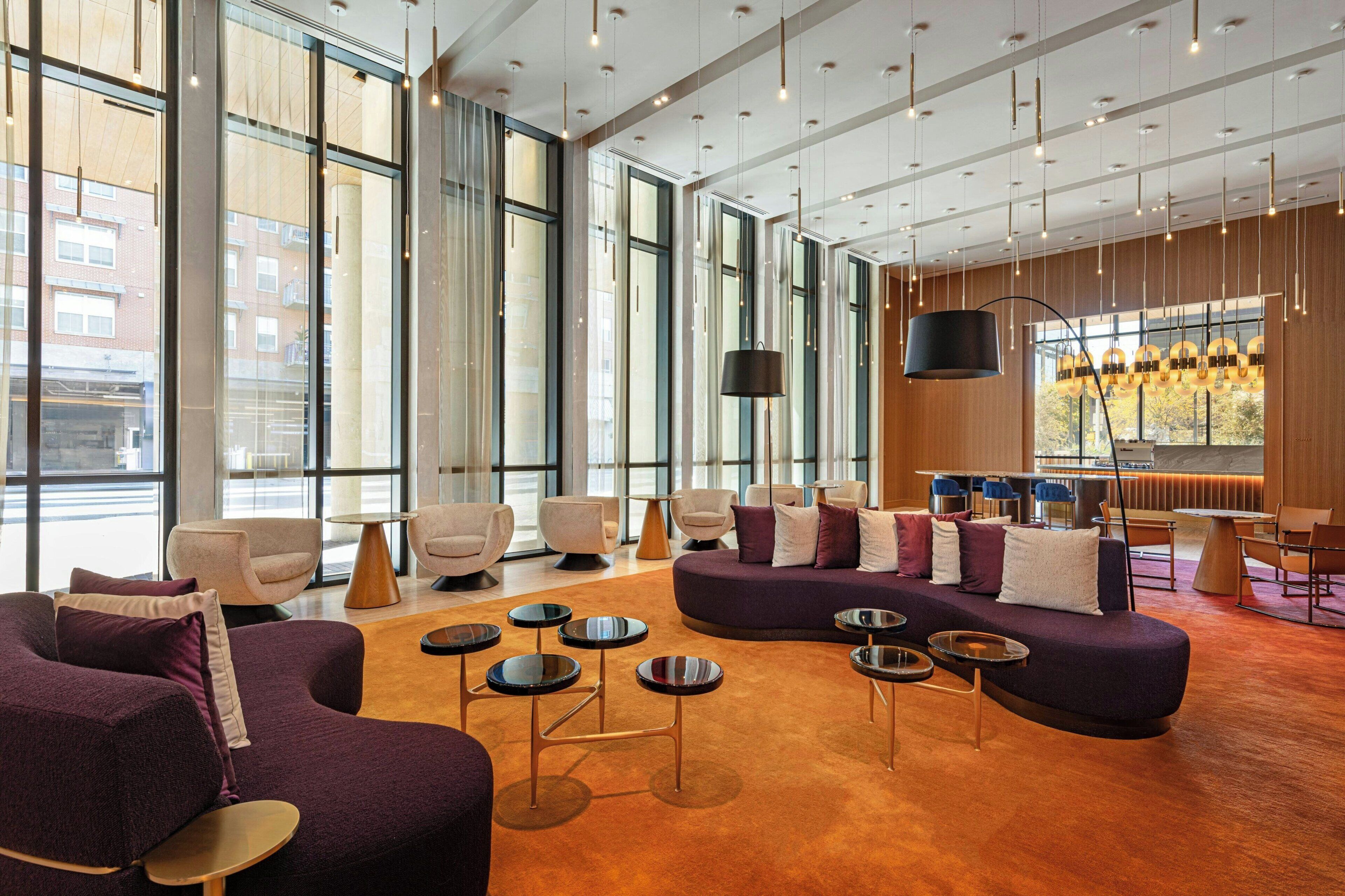 A spacious lobby with large windows, modern seating, and a bar area.