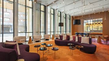 A spacious lobby with large windows, modern seating, and a bar area.