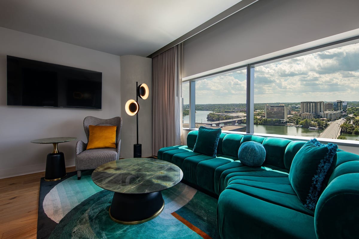 A modern living room with a large sofa, a round coffee table, a side table, and a flat-screen TV mounted on the wall.