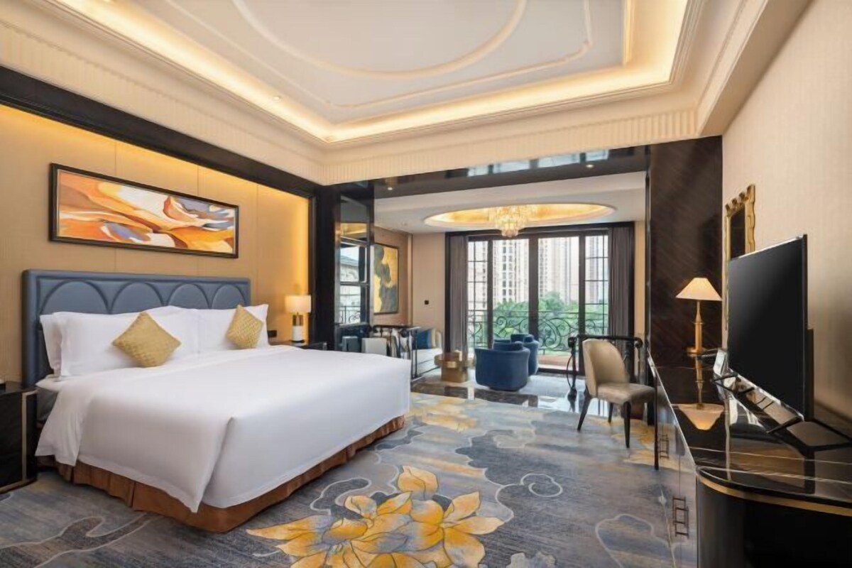 Une chambre d’hôtel avec un grand lit, un bureau avec une chaise, une télévision et une vue sur l’extérieur.