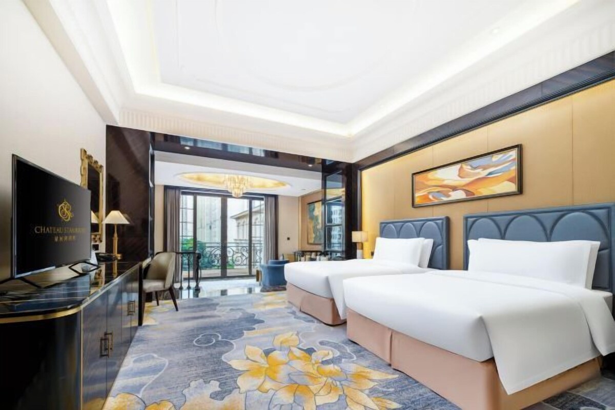 Une chambre d’hôtel équipée d’un lit, d’un bureau, d’une télévision et offrant une vue sur l’extérieur.