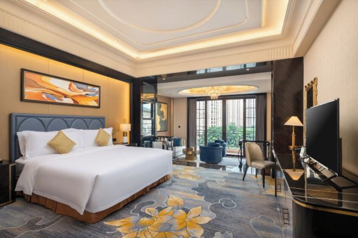 A hotel room with a large bed, a desk with a chair, a TV, and a view of the outdoors.