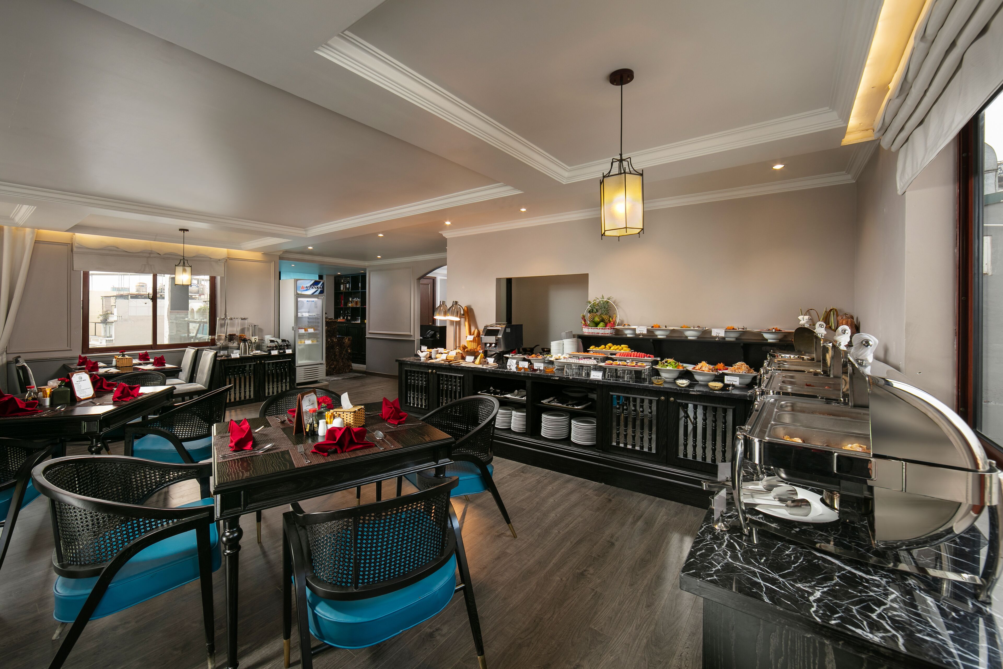 A hotel dining area with a buffet, seating arrangements, and a modern chandelier.