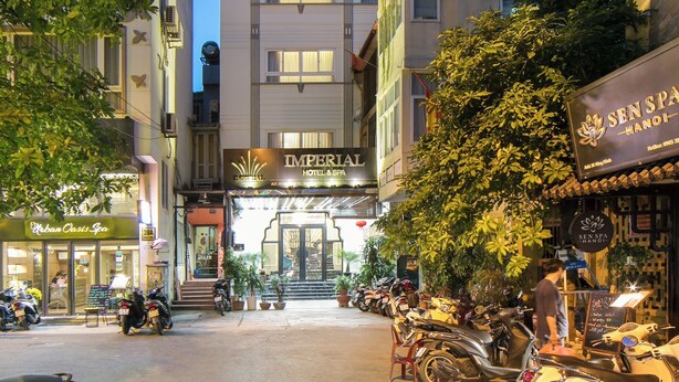 Um hotel com fachada moderna, entrada visível e uma fileira de scooters estacionadas.