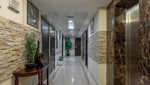 A hallway with a marble floor, wooden paneling, and a potted plant.