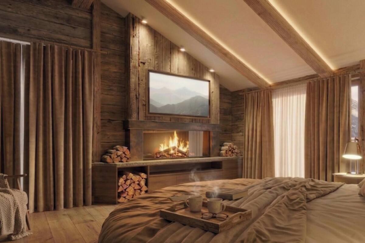 A cozy room with a fireplace, a bed, a TV mounted on the wall, and a wooden ceiling.
