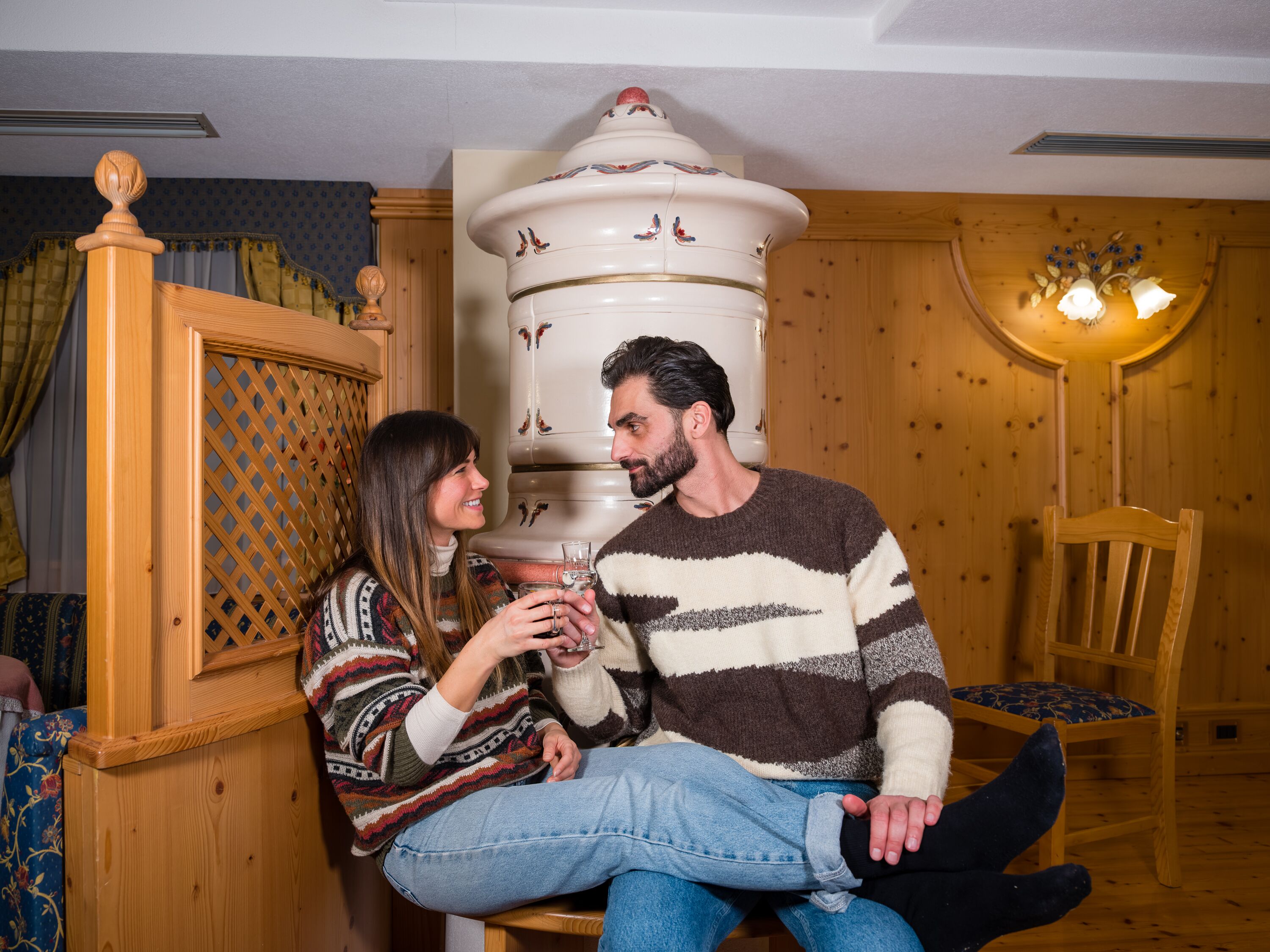 A couple sitting on a wooden bench in a room with wooden walls and a decorative white pillar.