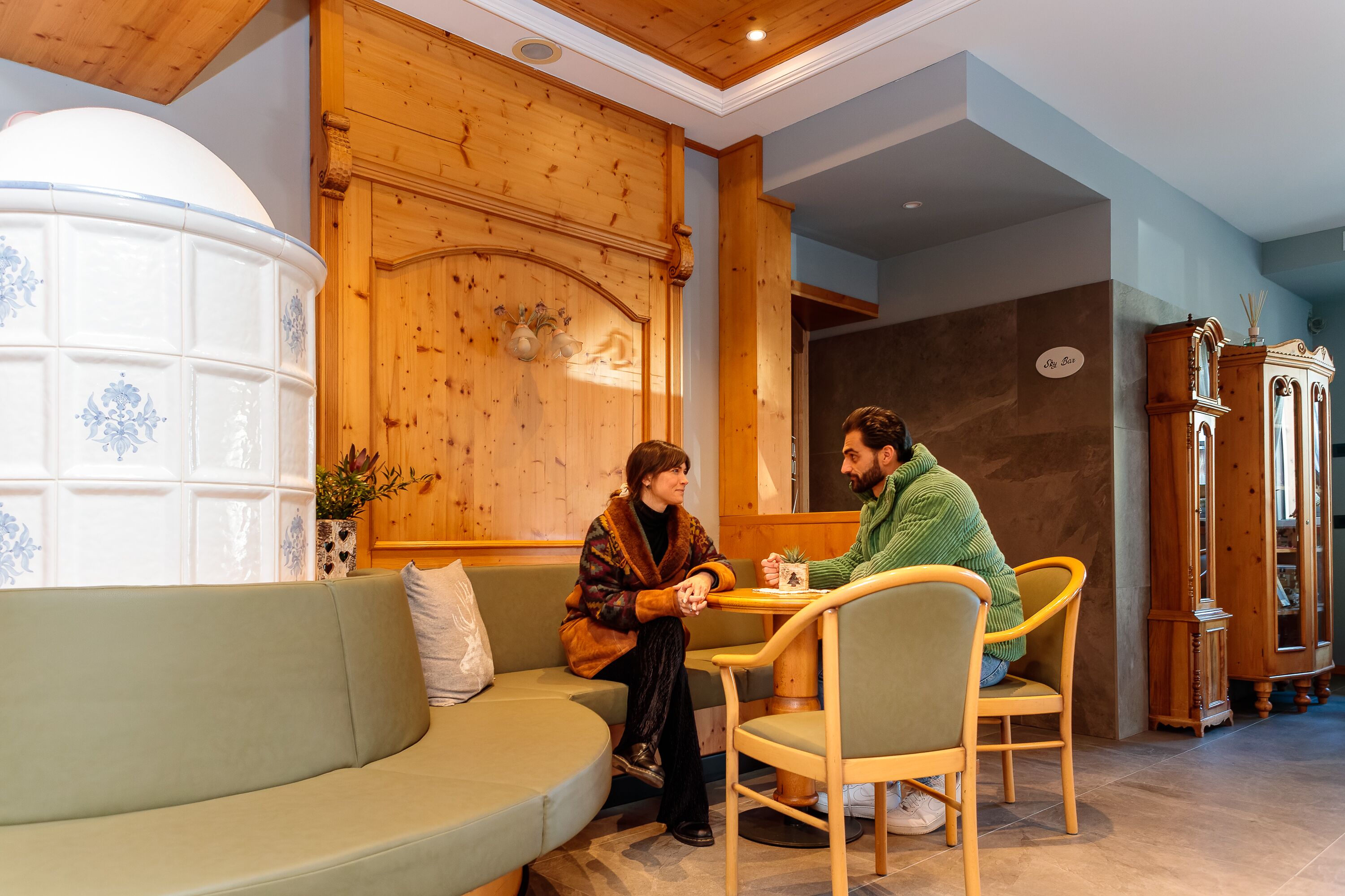 Ein gemütlicher Sitzbereich mit einer Holzwand, einer gepolsterten Bank und einem Tisch mit Stühlen.