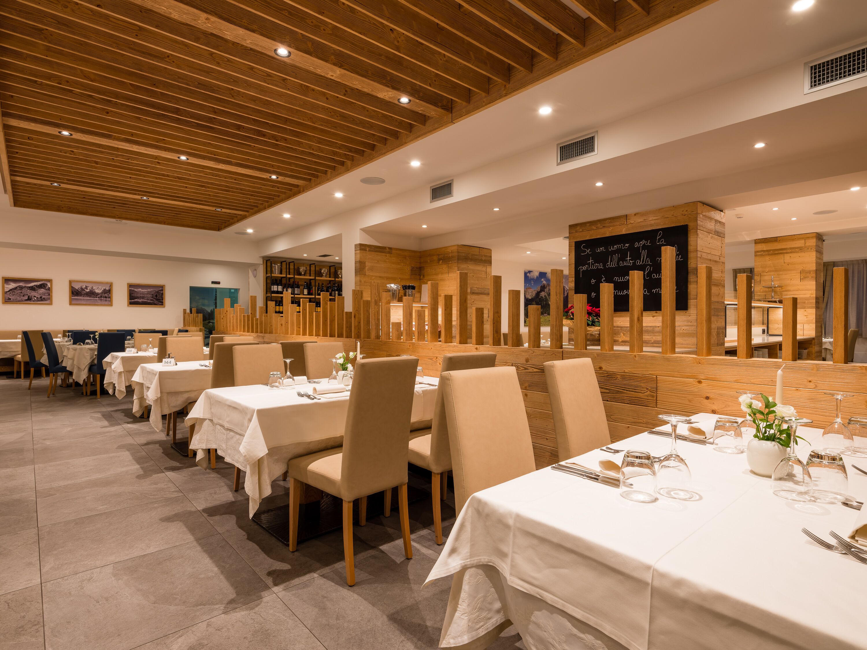 A restaurant with wooden ceiling beams, white tablecloths, and neatly set dining tables.