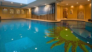 An indoor swimming pool with a sun design on the floor, skylights, and a mural of trees. - Albergo Dimaro Wellness & Family Hotel (Dimaro Folgarida)