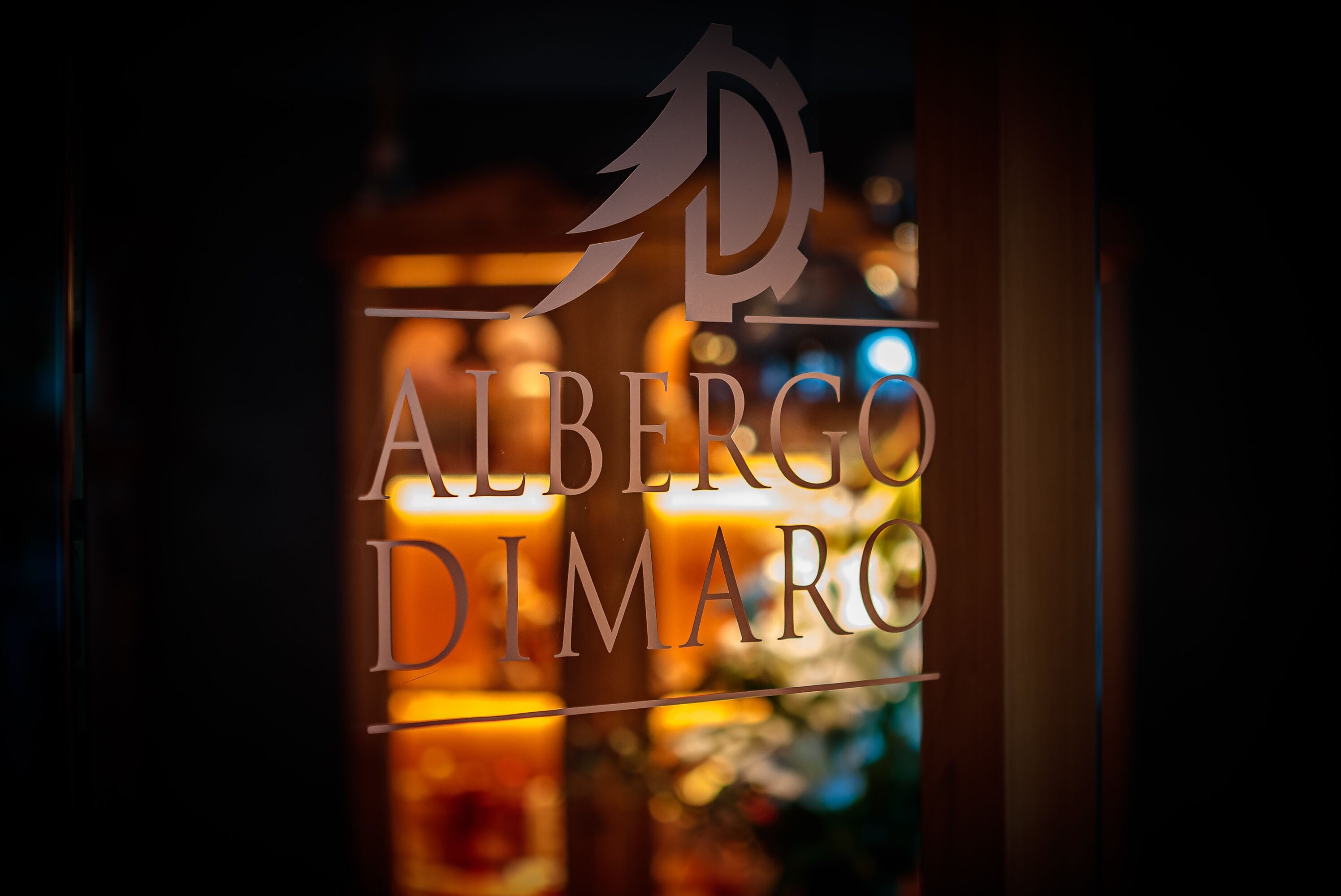A sign with the name "Albergo Dimaro" in a well-lit indoor setting.
