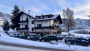 Een hotel met twee verdiepingen, met balkons, een stenen gevel en uitzicht op met sneeuw bedekte bergen.