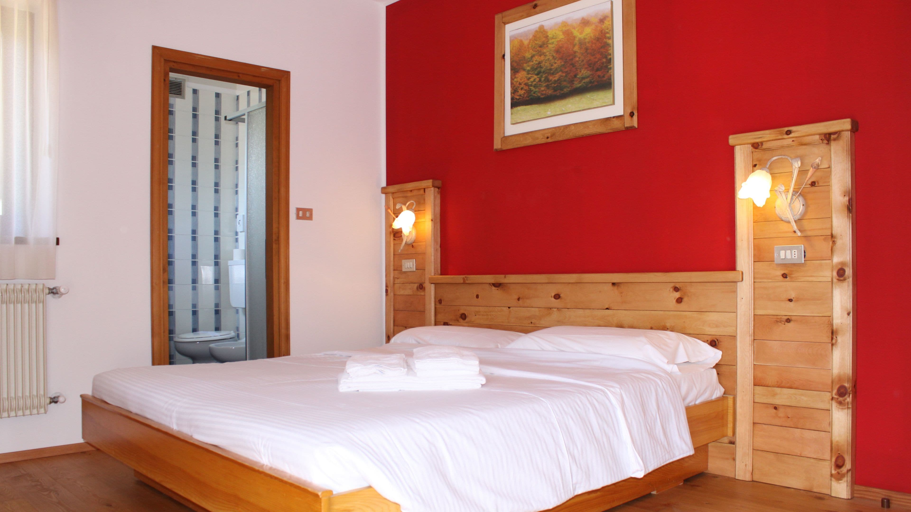 Una camera da letto con un letto di legno, pareti rosse e una finestra con tende.