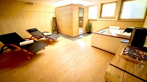 Een kamer met houten paneelwanden, een houten vloer, een klein houten kastje, een houten bureau met een computer en twee fauteuils.