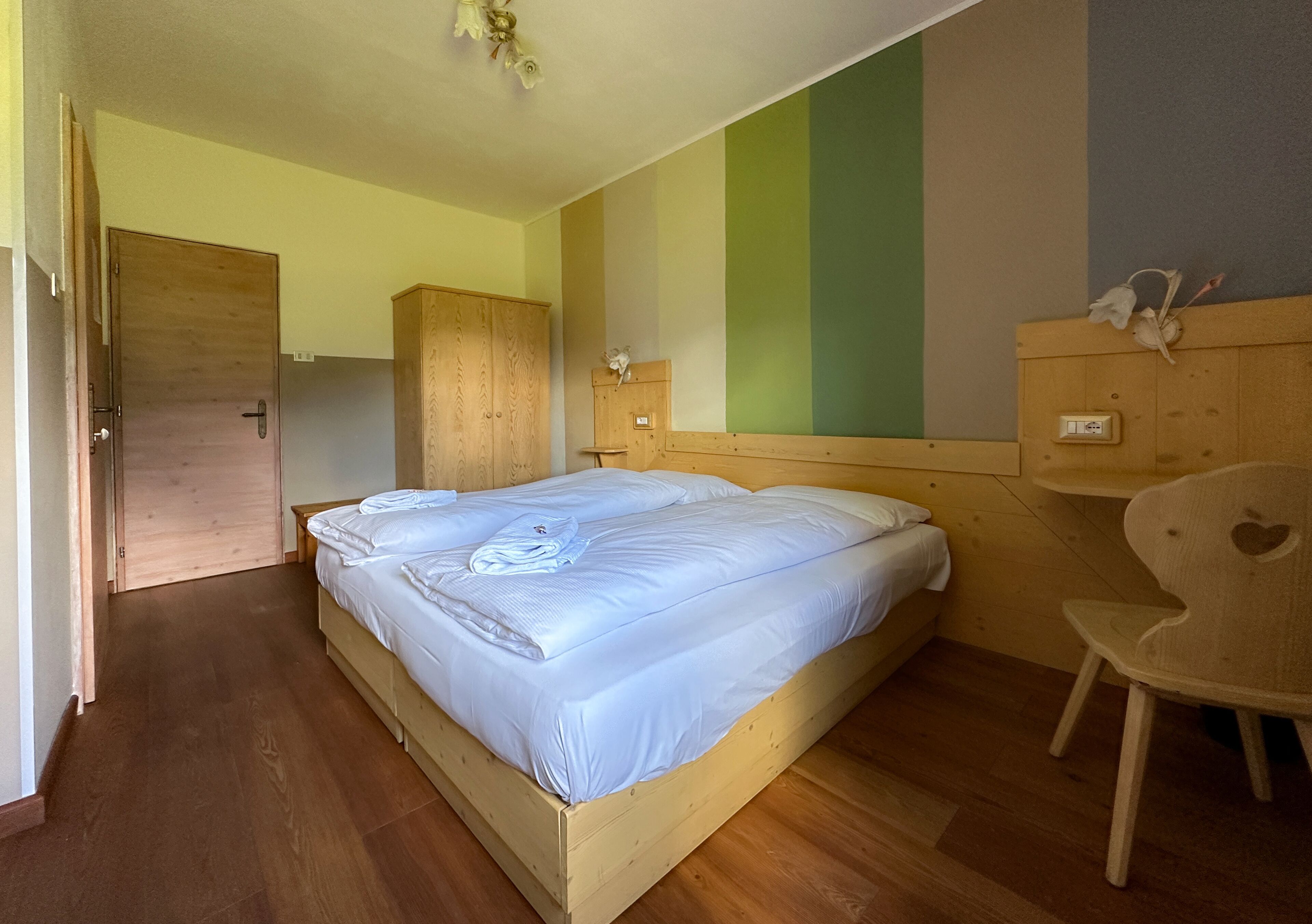Ein Schlafzimmer mit einem hölzernen Bett, einem Schrank, einem Nachttisch und einem Stuhl, alles aus Holz.