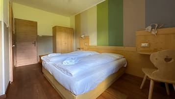 Ein Schlafzimmer mit einem hölzernen Bett, einem Schrank, einem Nachttisch und einem Stuhl, alles aus Holz.