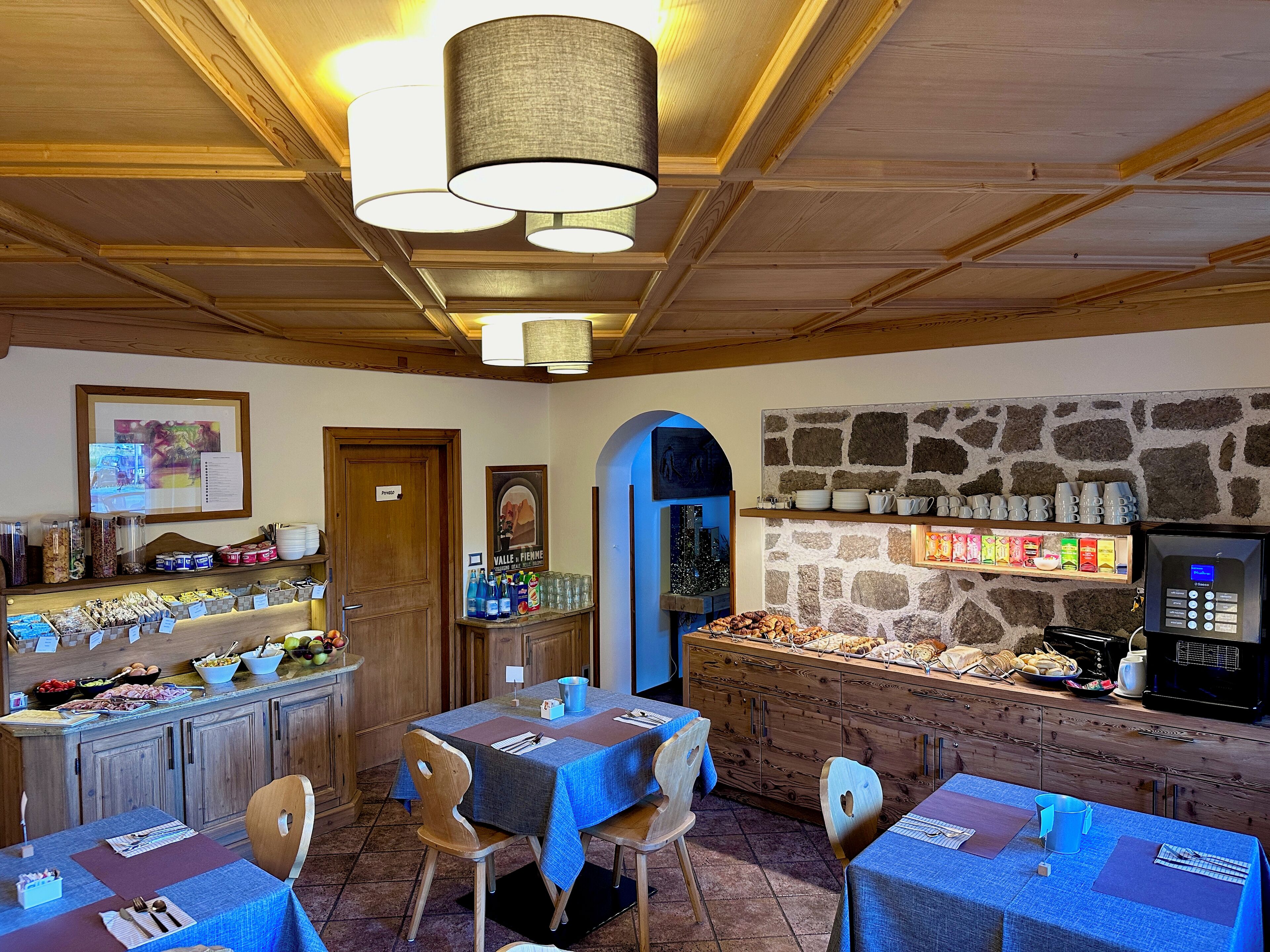 Un restaurant chaleureux, avec des meubles en bois, un mur en pierre et un large choix de plats et de boissons.