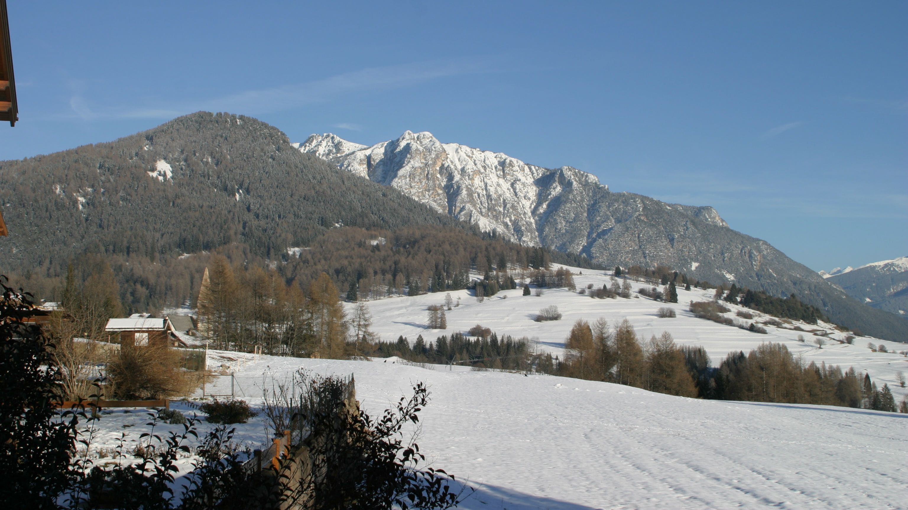 A snow-covered landscape with mountains in the background and a clear sky.