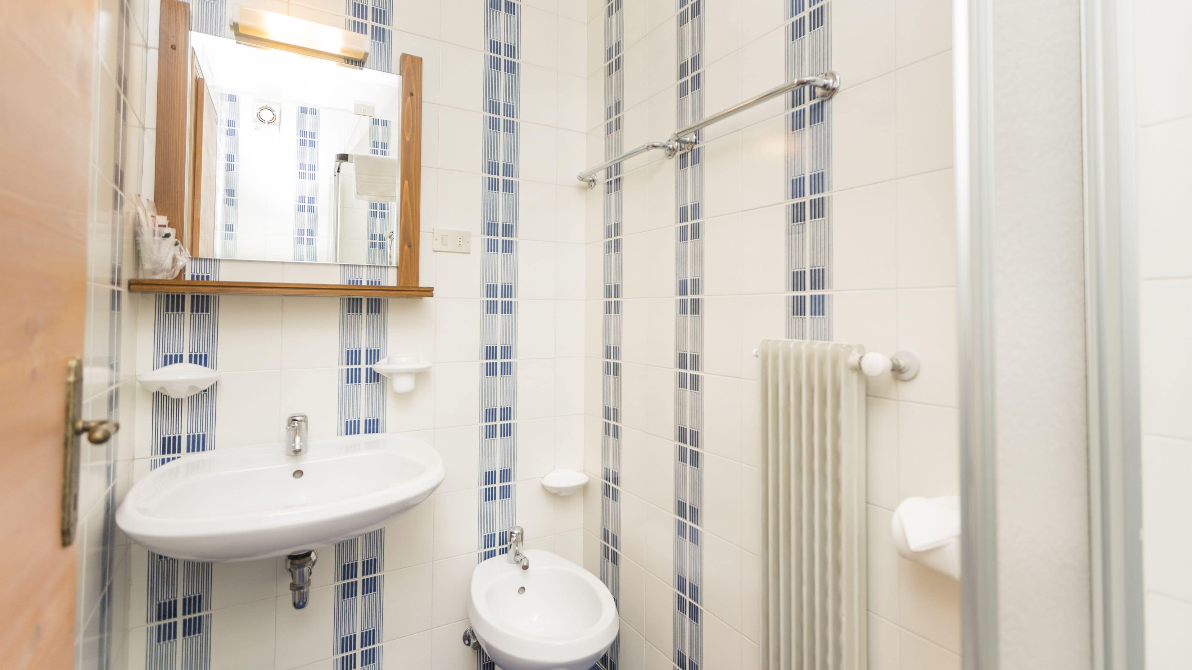 Un baño con lavamanos blanco, un espejo y un toallero.