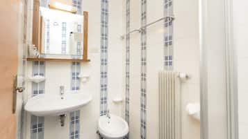 Un baño con lavamanos blanco, un espejo y un toallero.
